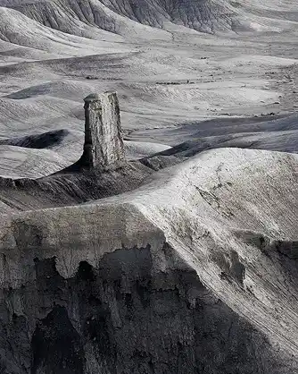 Lone Butte Surrounded by Eroded Hills Black and white photo of a lone rocky butte surrounded by textured eroded hills, taken by Bob Hart in Hanksville, Utah after sunrise.