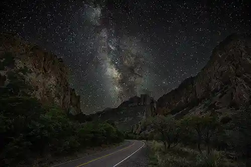 Milky Way Above Chisos Basin Road Night photo of the Milky Way above Chisos Basin Road in Big Bend National Park, with high cliffs framing the scene. Image by Dale Sullivan.