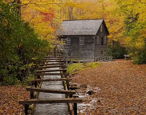 Mingus Mill, Smokies Photo of Mingus Mill in autumn with a wooden water chute leading toward the historic structure, surrounded by vivid fall foliage. Taken by Rick Thompson in Great Smoky Mountains National Park.