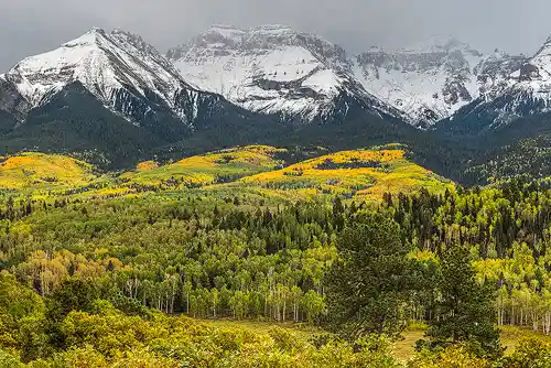 Storm Over the San Juans Autumn landscape near Ridgway, Colorado with colorful aspen and scrub oak in the foreground and snow-capped San Juan Mountains under storm clouds. Image by Mark Leatherman.
