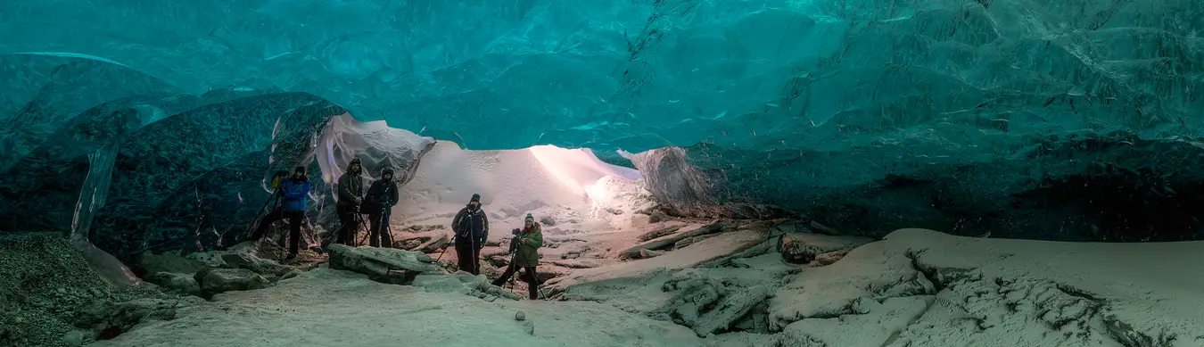 Panorama of five photographers posing in an ice cave, surrounded by blue ice.