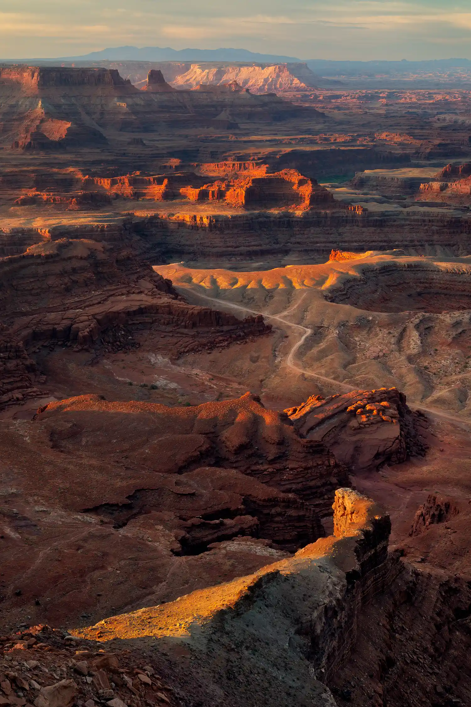 Sunrise at Dead Horse Point with orange dawn light over Canyonlands cliffs and mesas.
