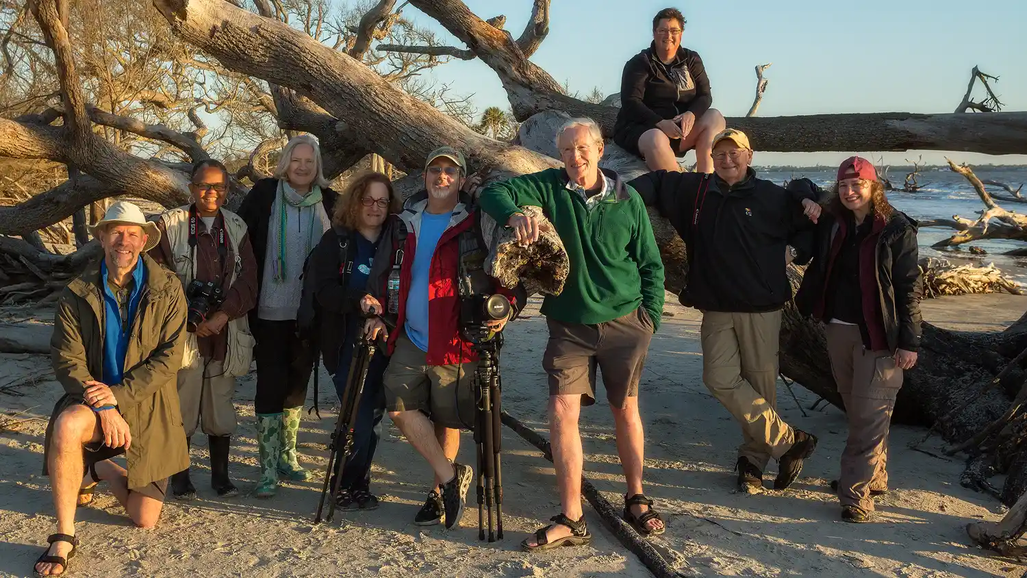 Group photo of photography workshop participants on a beach.