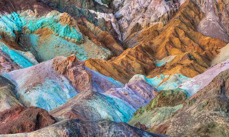 Workshop location; Artist Palette, Death Valley National Park, California. These mounds of rock are a colorful blend of orange, red, green, turquoise, pink, brown and blue. As if many flavors of Baskin Robbins ice cream were piled together turned to stone then eroded into attractively carved drainage patterns.