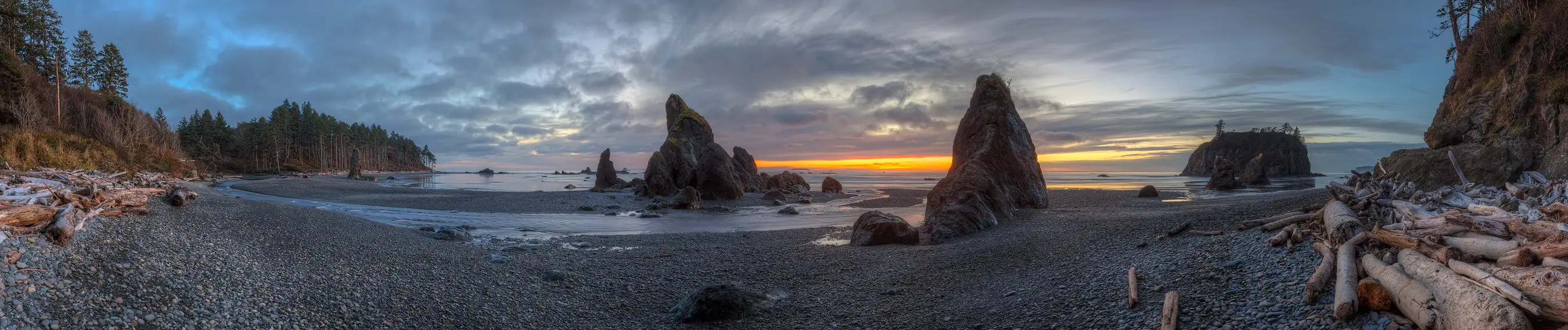 Panoramic sunset view of Second Beach with sea stacks, rocky shoreline, and dramatic clouds.