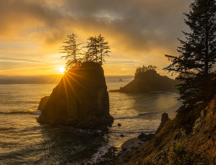 Dramatic sunset over sea stack with sun star at Samuel H. Boardman State Scenic Corridor.