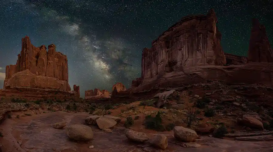 Milky Way rising between towering sandstone monoliths in Arches National Park.
