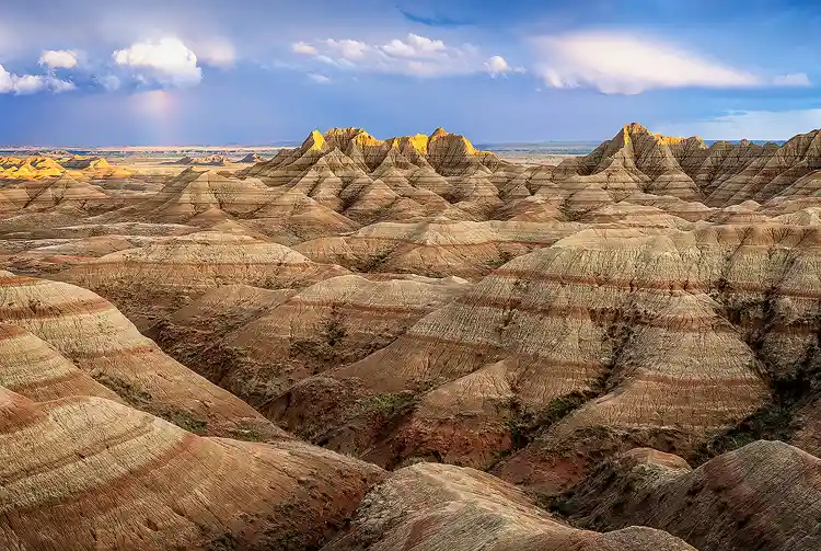 Late afternoon light illuminating layered buttes and ridges in Badlands National Park.