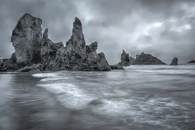 Sea stacks and long-exposure surf beneath storm clouds on Bandon Beach along the Oregon coast.