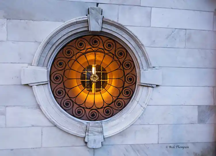 Warm light glowing through a circular window with decorative ironwork in Charleston.