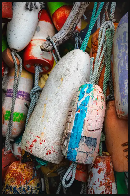 Weathered fishing floats and ropes hanging together in a working harbor along the Oregon coast.