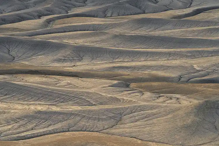 Bands of warm morning light sweeping across rolling badlands at Moonscape Overlook near Hanksville, Utah.