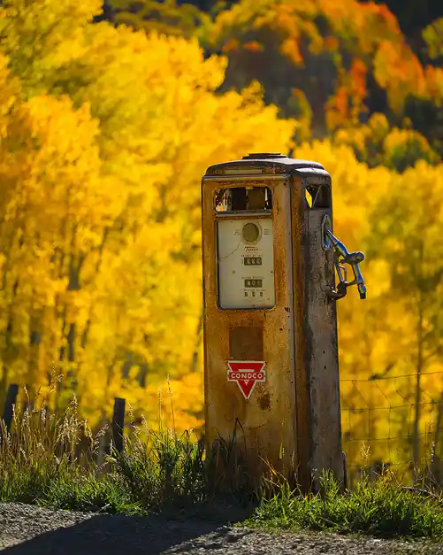 Vintage Conoco gasoline pump against a backdrop of golden aspens in the San Juan Mountains of Colorado.