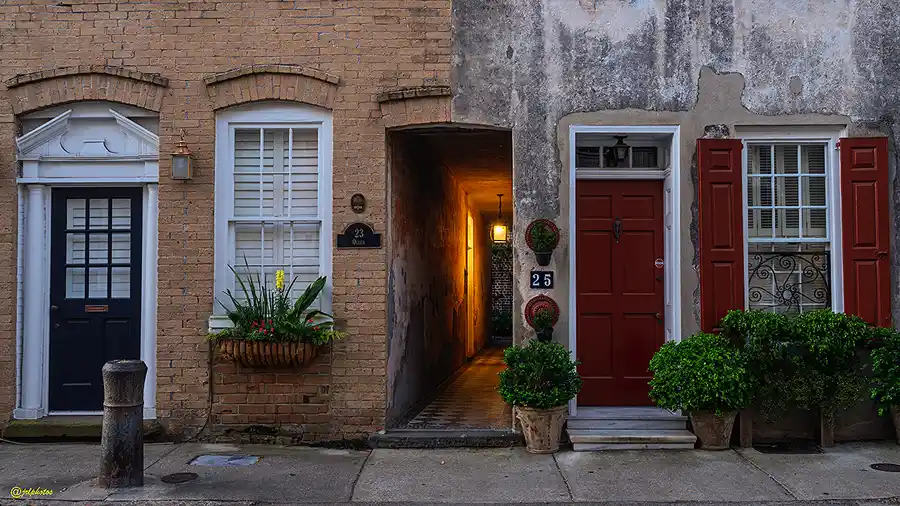 Warmly lit passageway between historic Charleston homes.