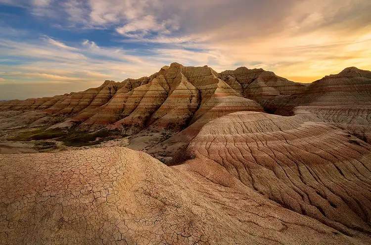 Last light of sunset warming layered badlands beyond gently eroded ridges in Badlands National Park.