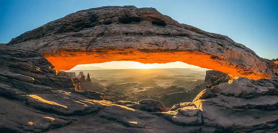 Sunrise illuminating the glowing underside of Mesa Arch above the canyons of Canyonlands National Park.