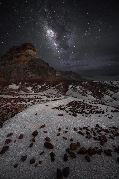 The Milky Way rising above Cerro Castellan with white volcanic ash and scattered red rocks in Big Bend National Park.