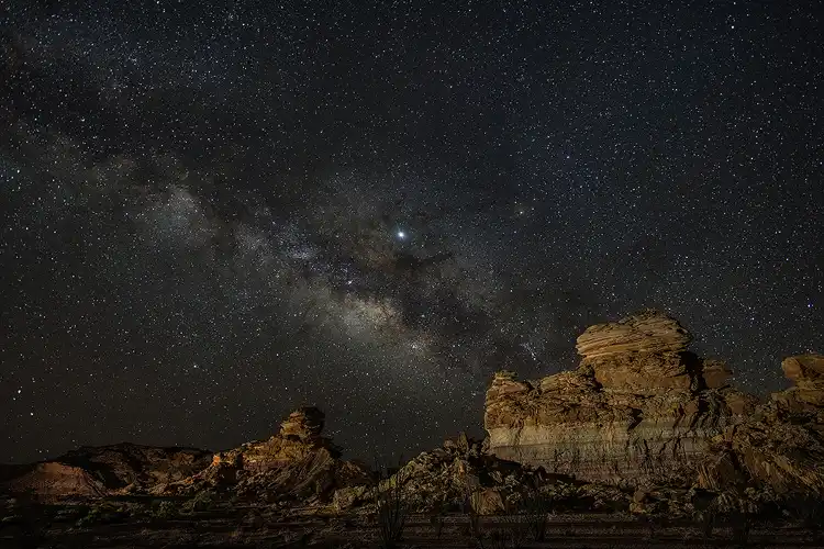 The Milky Way stretching above layered volcanic rock formations at Exhibit Ridge in Big Bend National Park.