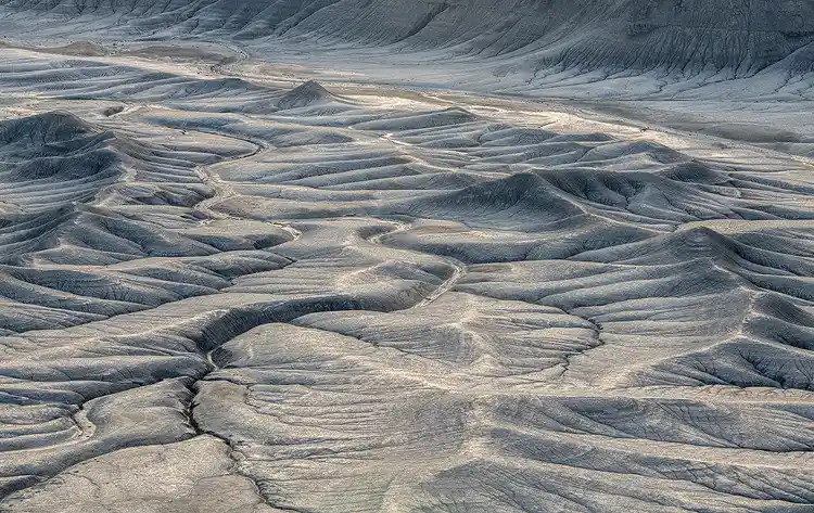 Morning light tracing across rolling badlands at Moonscape Overlook near Hanksville, Utah.