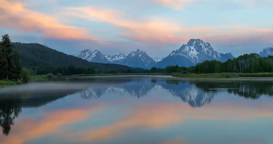 Morning reflections of Mount Moran in the Snake River at Oxbow Bend beneath pastel sunrise clouds, Grand Teton National Park.