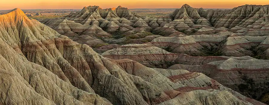 Sunset light catching layered ridges as the Badlands unfold toward the horizon in Badlands National Park.