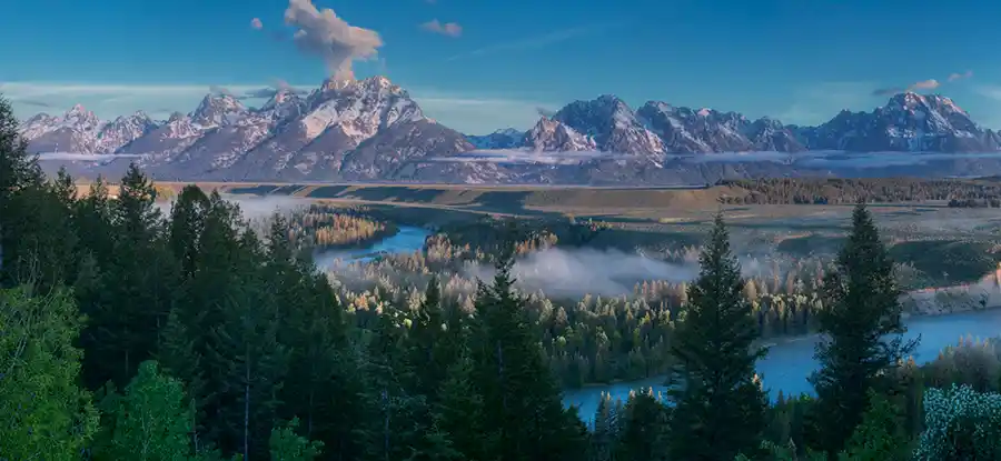 Low morning fog drifting through Jackson Hole beneath the Teton Range from Snake River Overlook, Grand Teton National Park.