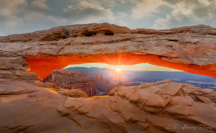 Sunstar shining through Mesa Arch above the canyons of Canyonlands National Park.