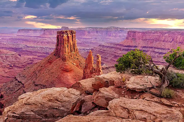 Towering sandstone monolith rising above a vast canyon beneath dramatic evening skies at Marlboro Point near Canyonlands National Park.