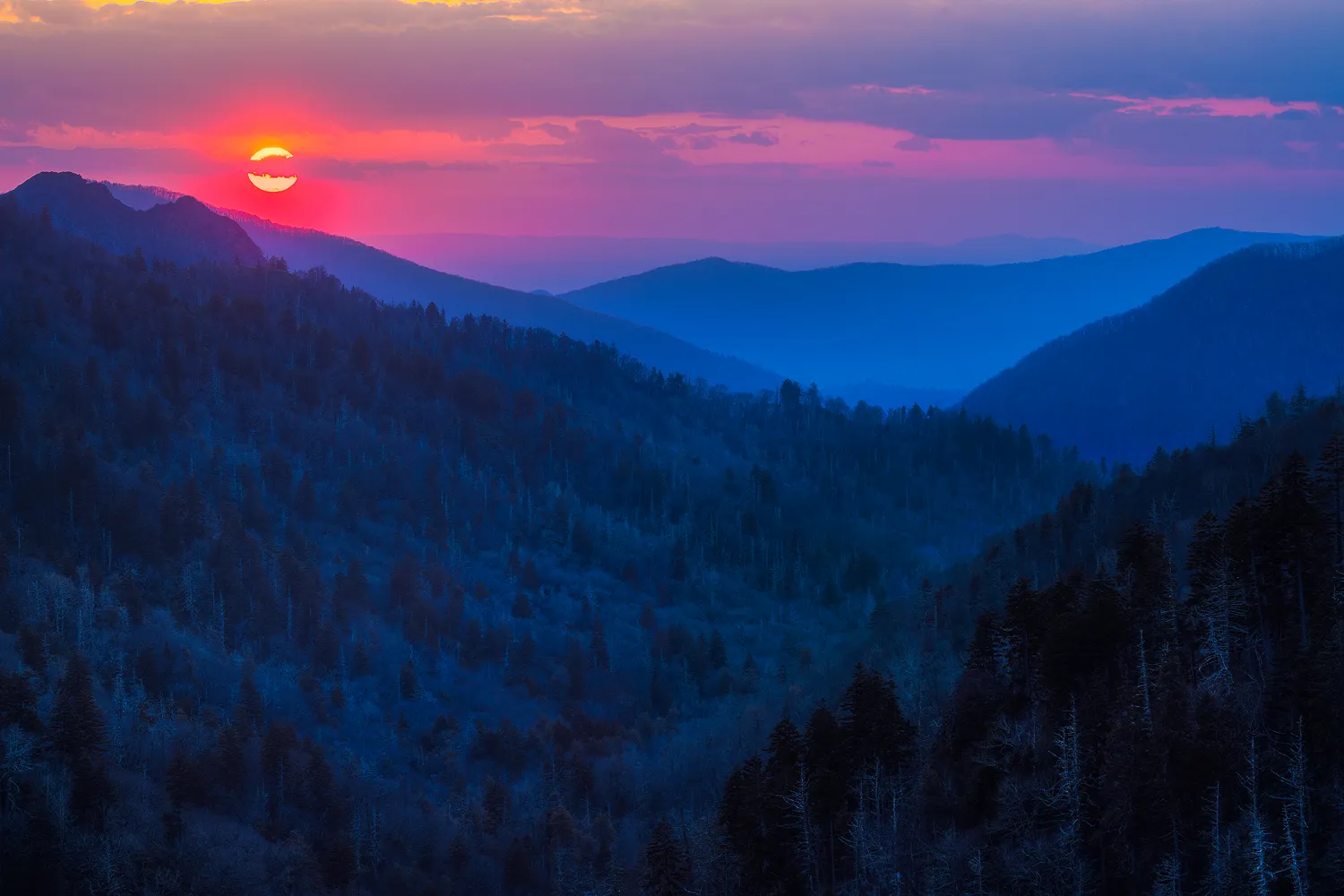 Layered blue ridges under a red sky at sunset in the Smoky Mountains in spring.