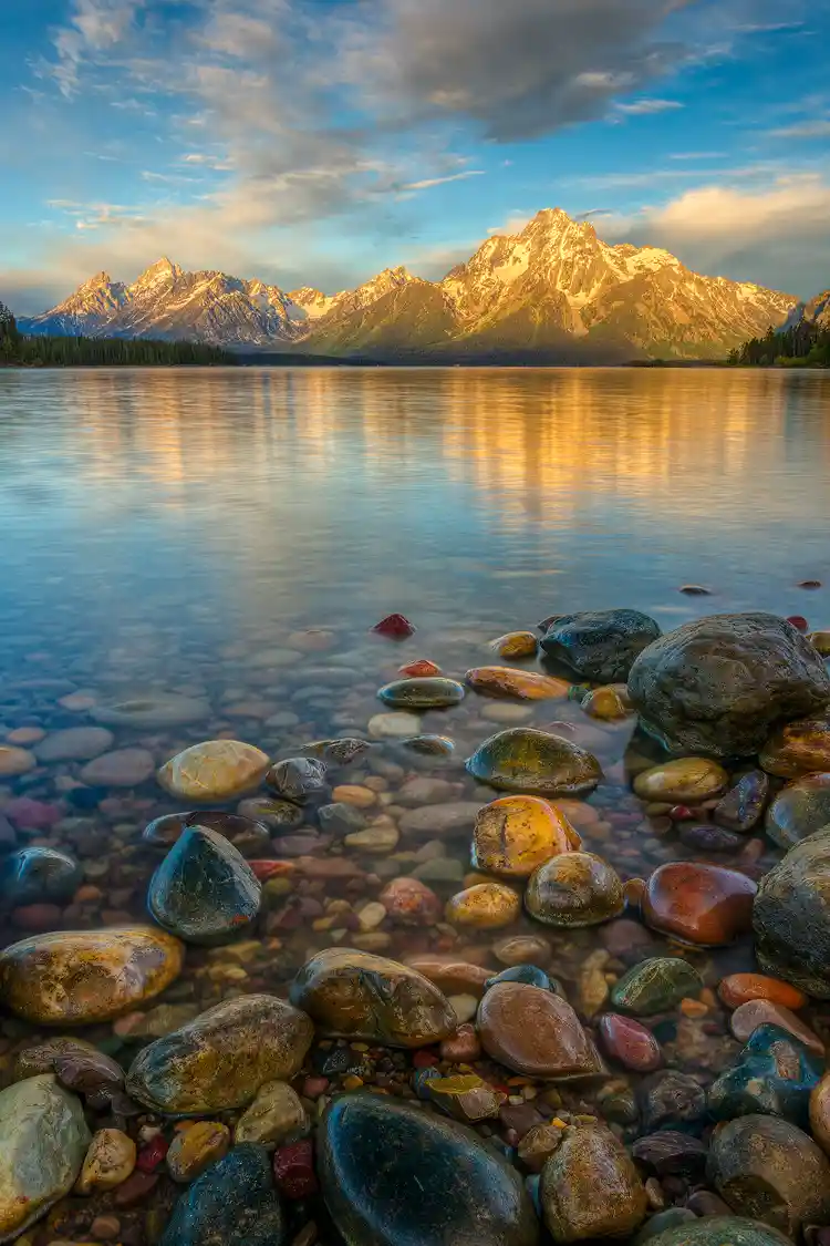 Workshop location; Smooth, round, wet stones at waters edge make up the foreground of this morning photo of Mount Moran reflecting in Jackson Lake, Grand Teton National Park.